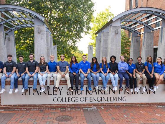 Group of Engineering Ambassadors sitting on Pigman College of Engineering sign in engineering courtyard